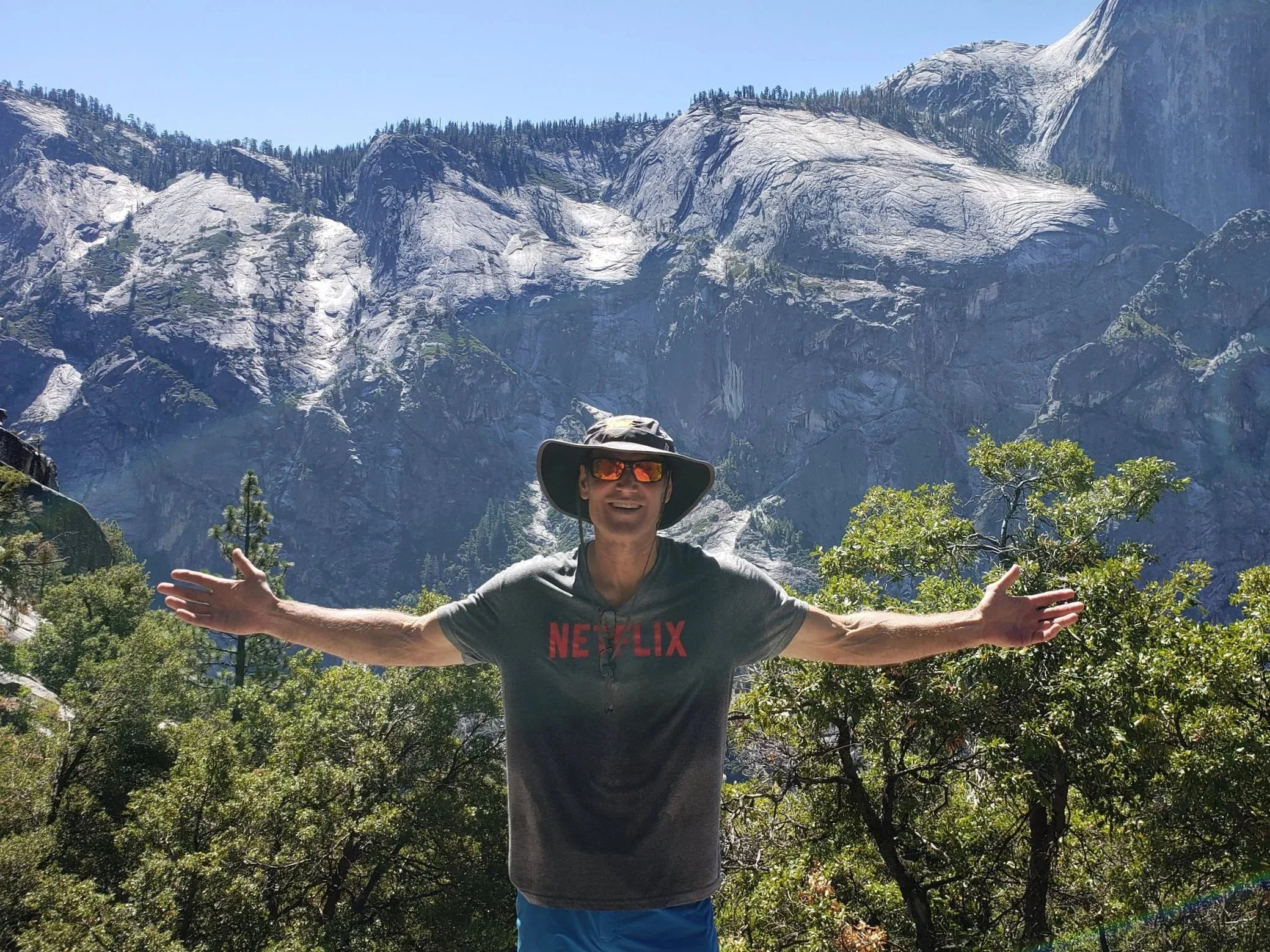Rod Wilson with his arms wide on a trail in Yosemite